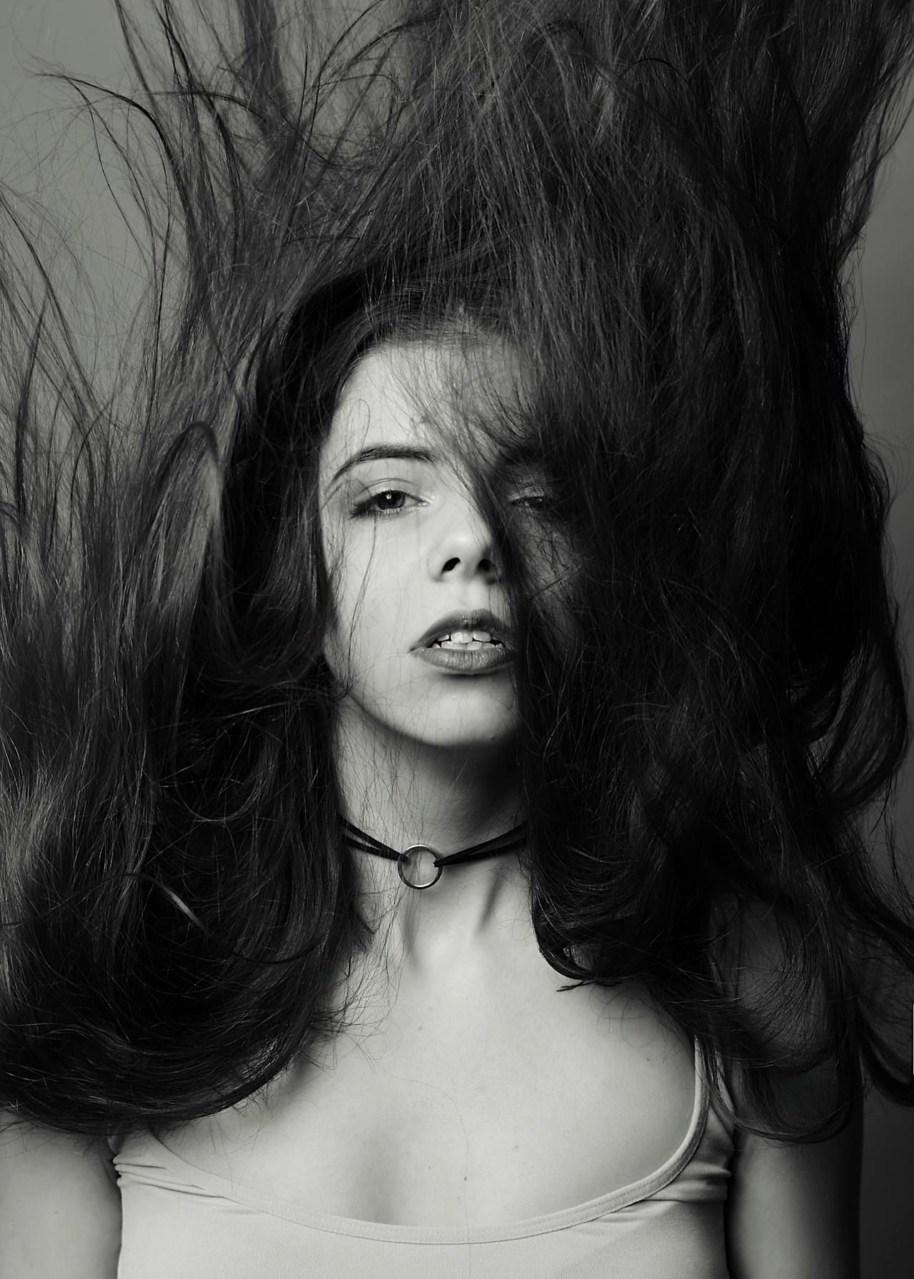 A black and white photo of a woman with her hair blowing in the wind.