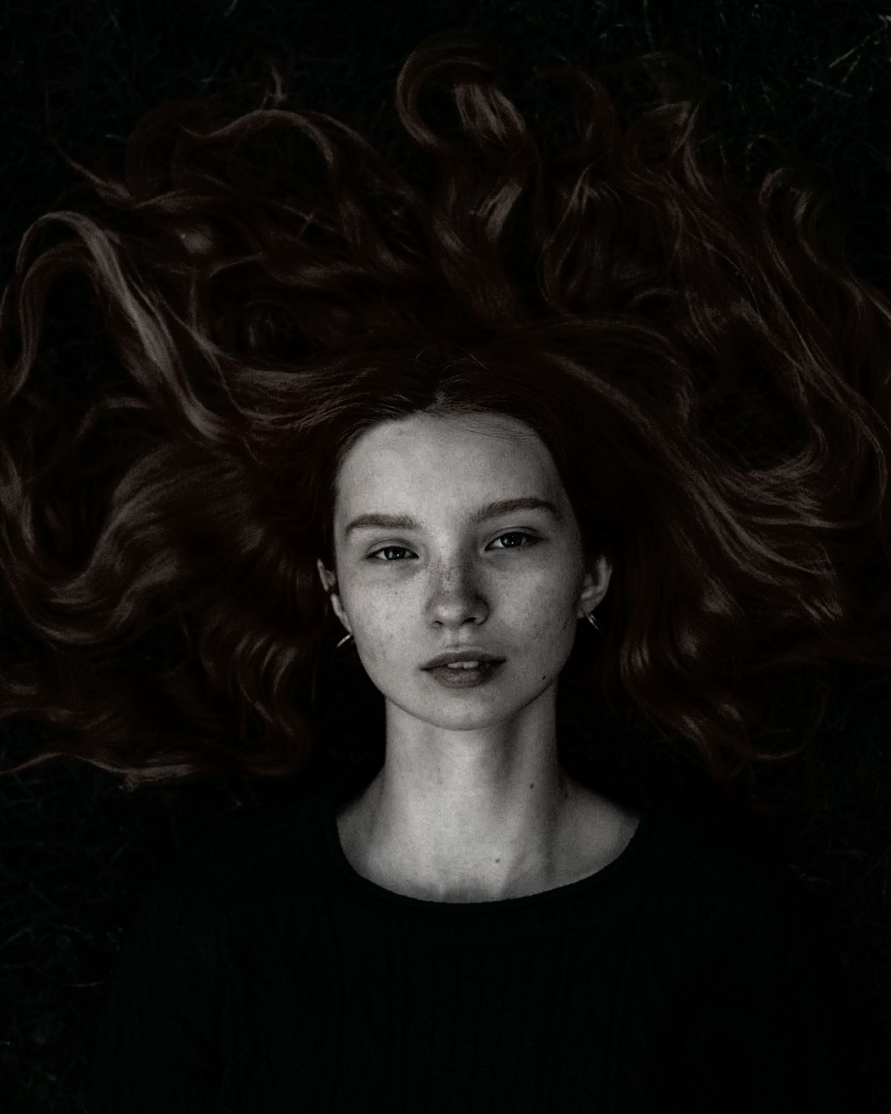 A black and white photo of a woman with her hair blowing in the wind.