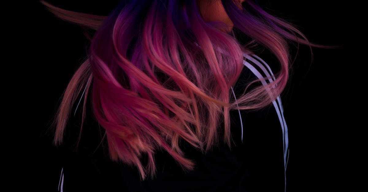 A close up of a woman 's pink and purple hair on a black background.