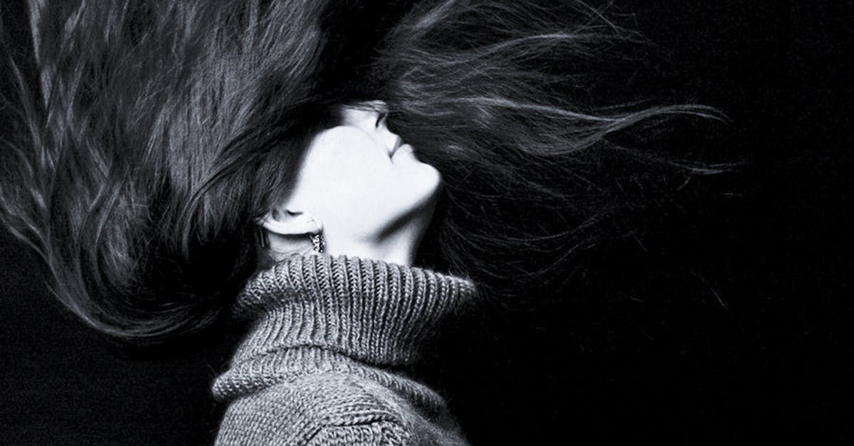 A black and white photo of a woman with her hair blowing in the wind.