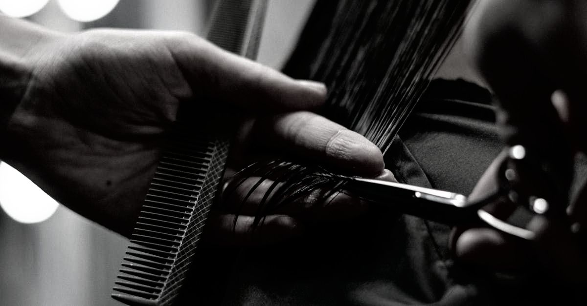 A person is cutting their hair with scissors and a comb.