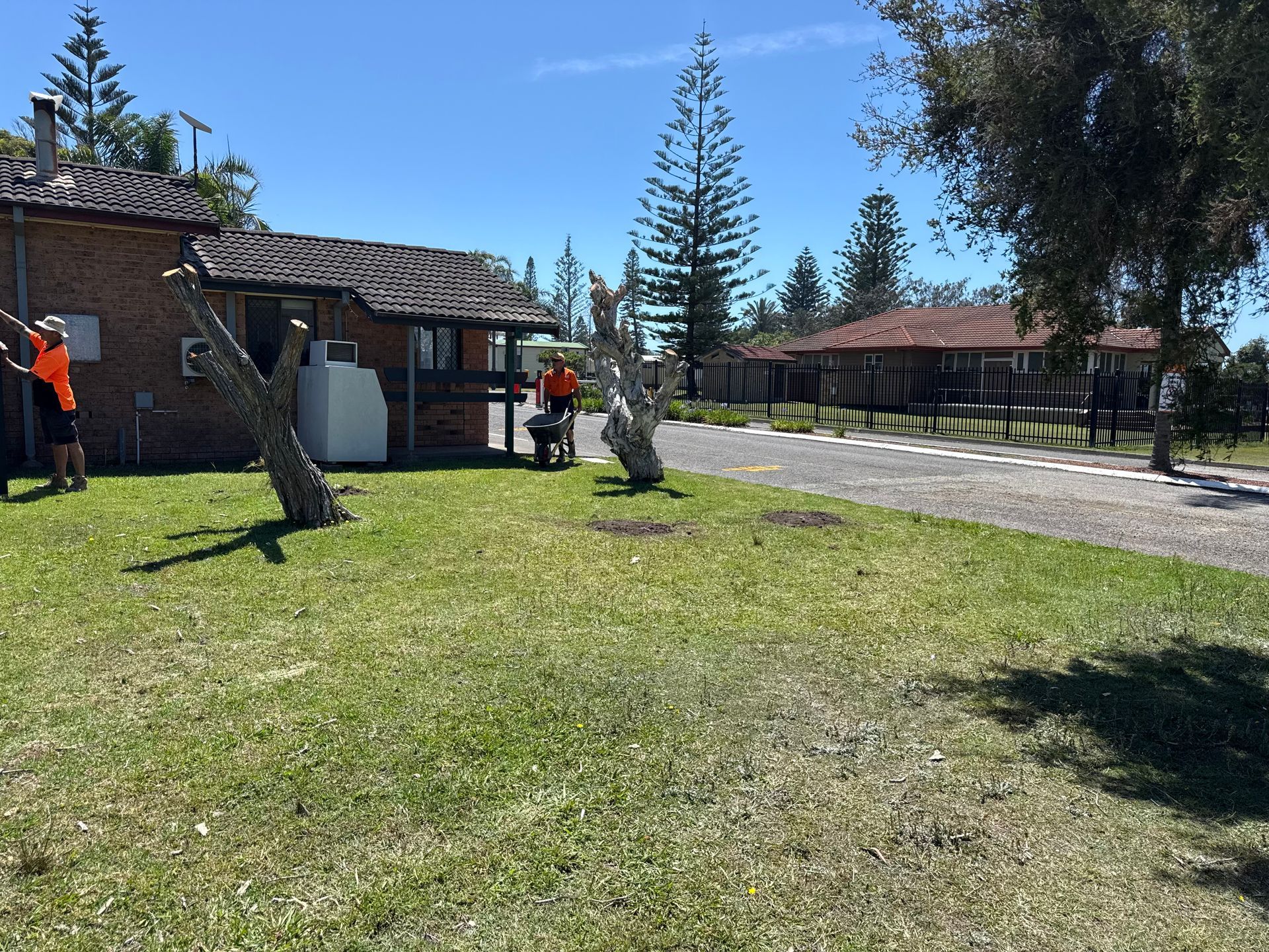 People working near buildings on a sunny day. Green grass and trees in foreground.  - A1 Maintenance and Building In Old Bar, NSW