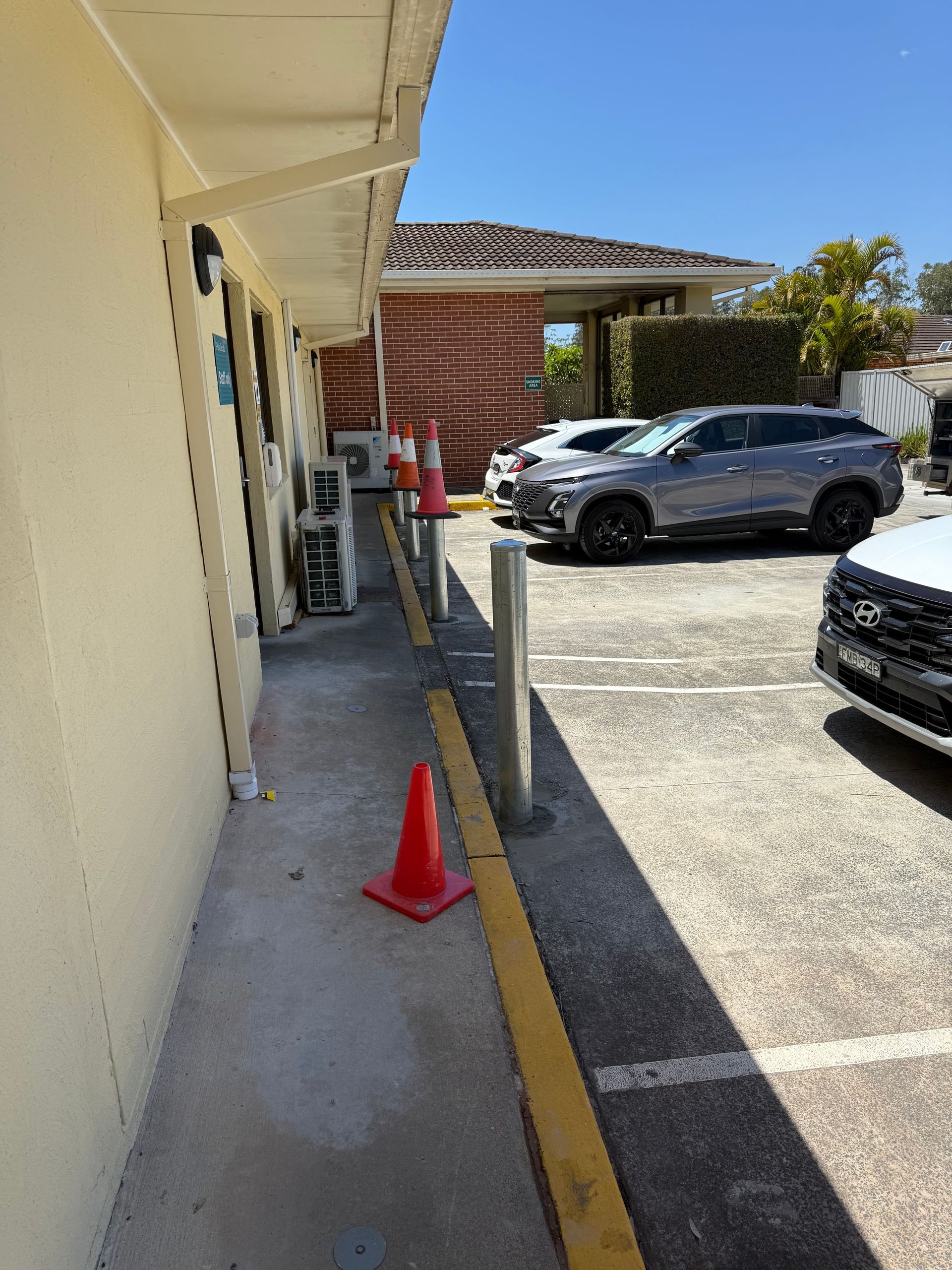 Exterior view of building with parked cars. Orange cones line the sidewalk next to a yellow curb  - A1 Maintenance and Building, NSW