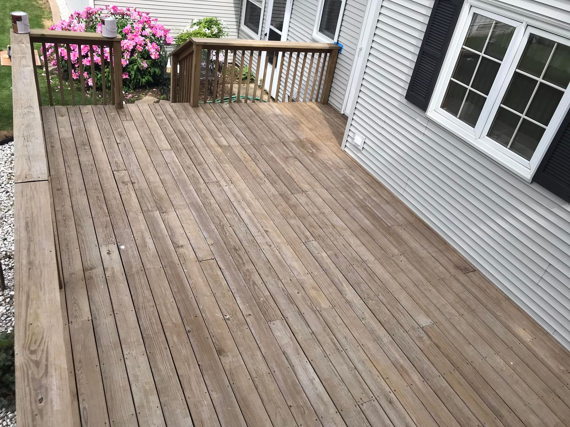 A wooden deck is sitting in front of a house.