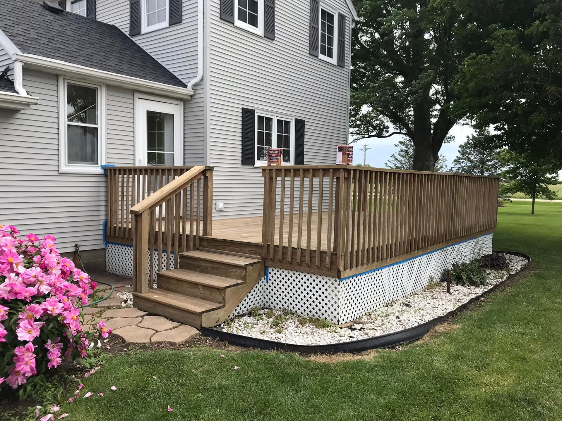 A wooden deck with stairs is in front of a house.