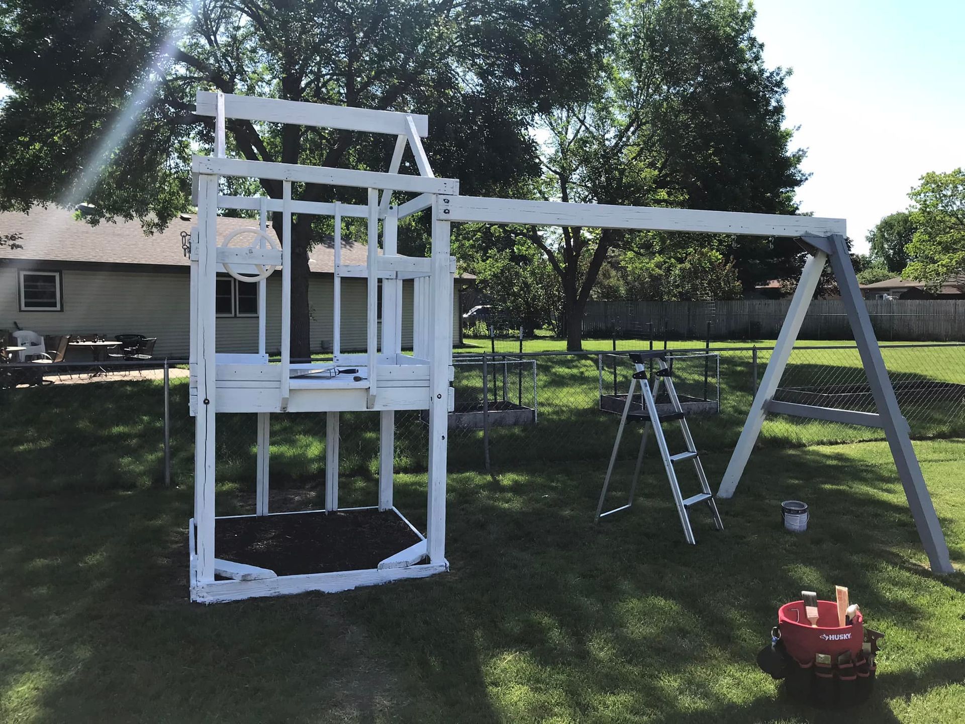 A white swing set is sitting in the grass in front of a house