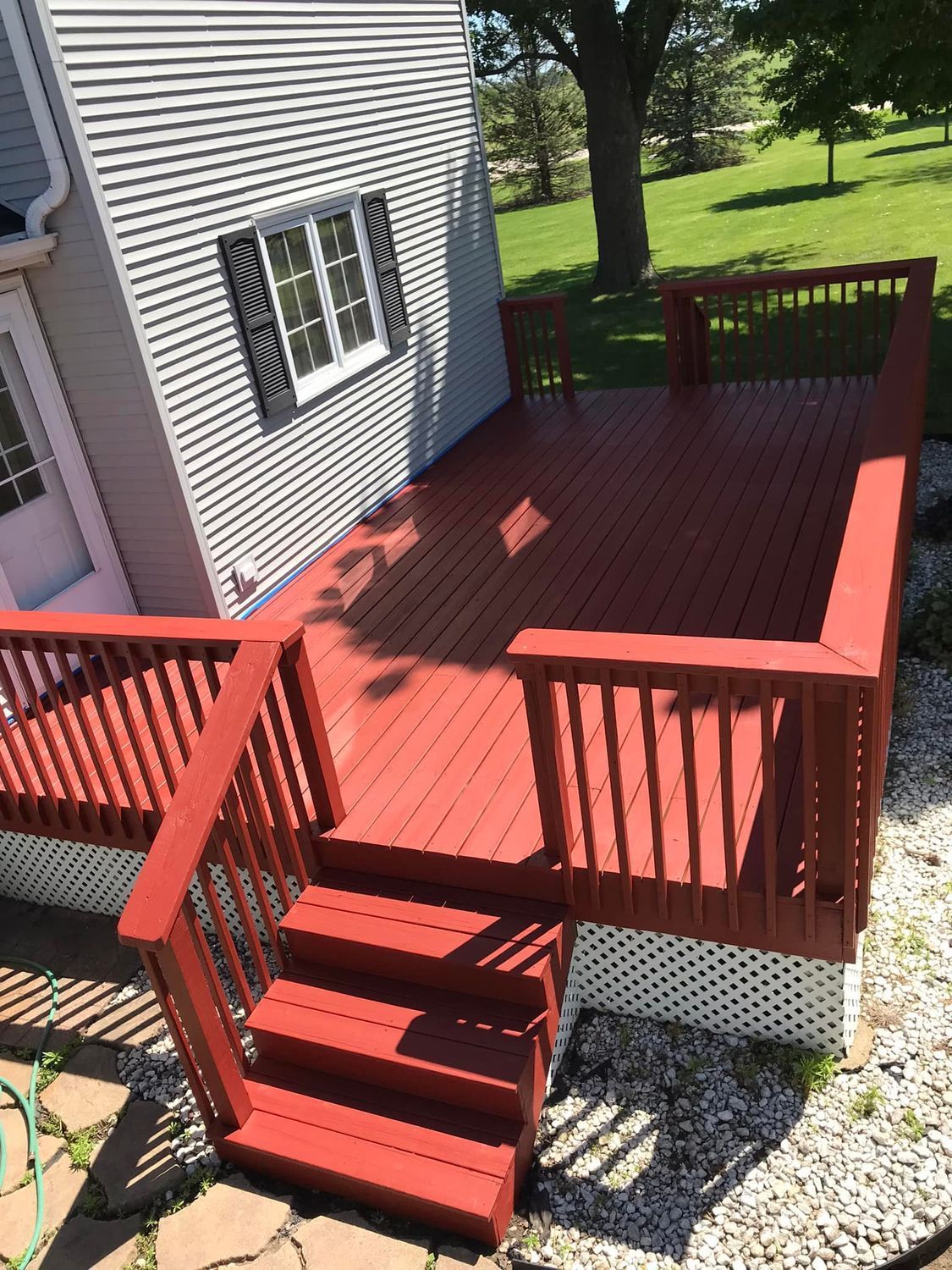 A red deck with stairs and a white house in the background