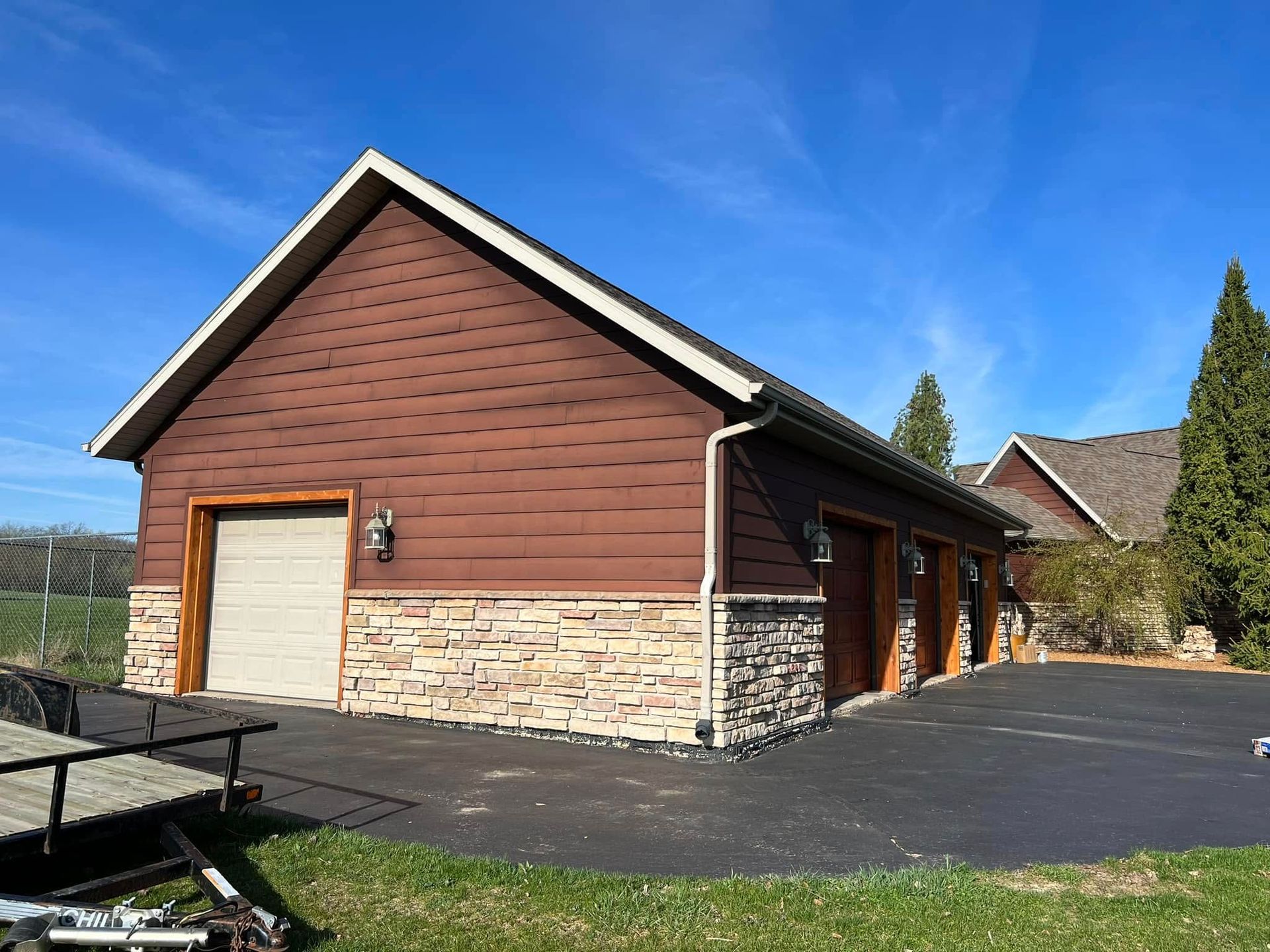 A large brown garage with two garage doors and a picnic table in front of it.