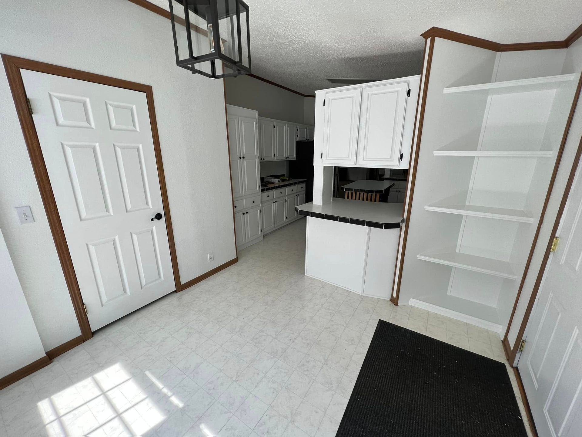 A kitchen with white cabinets and a black rug