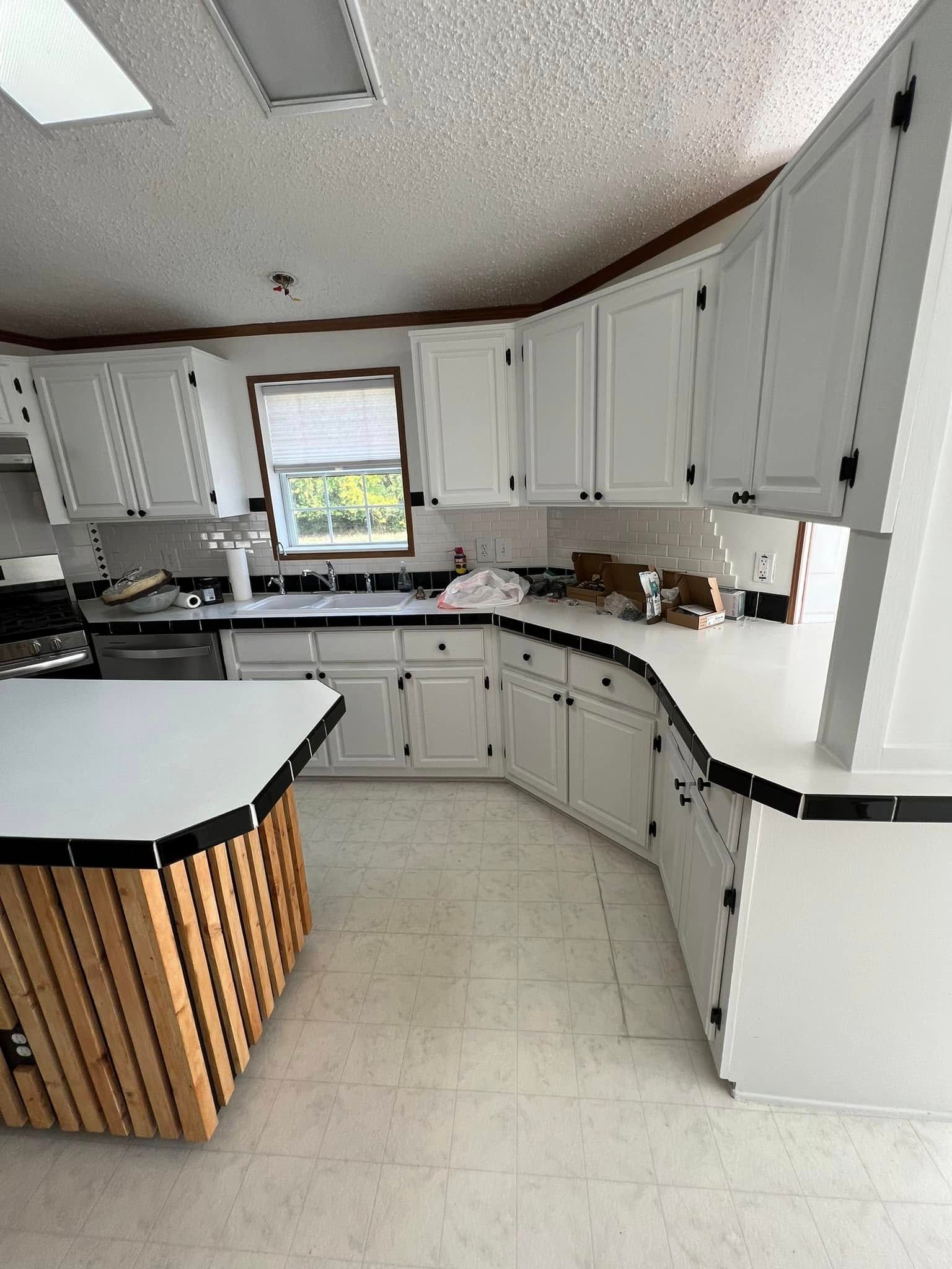 A kitchen with white cabinets and a wooden island.