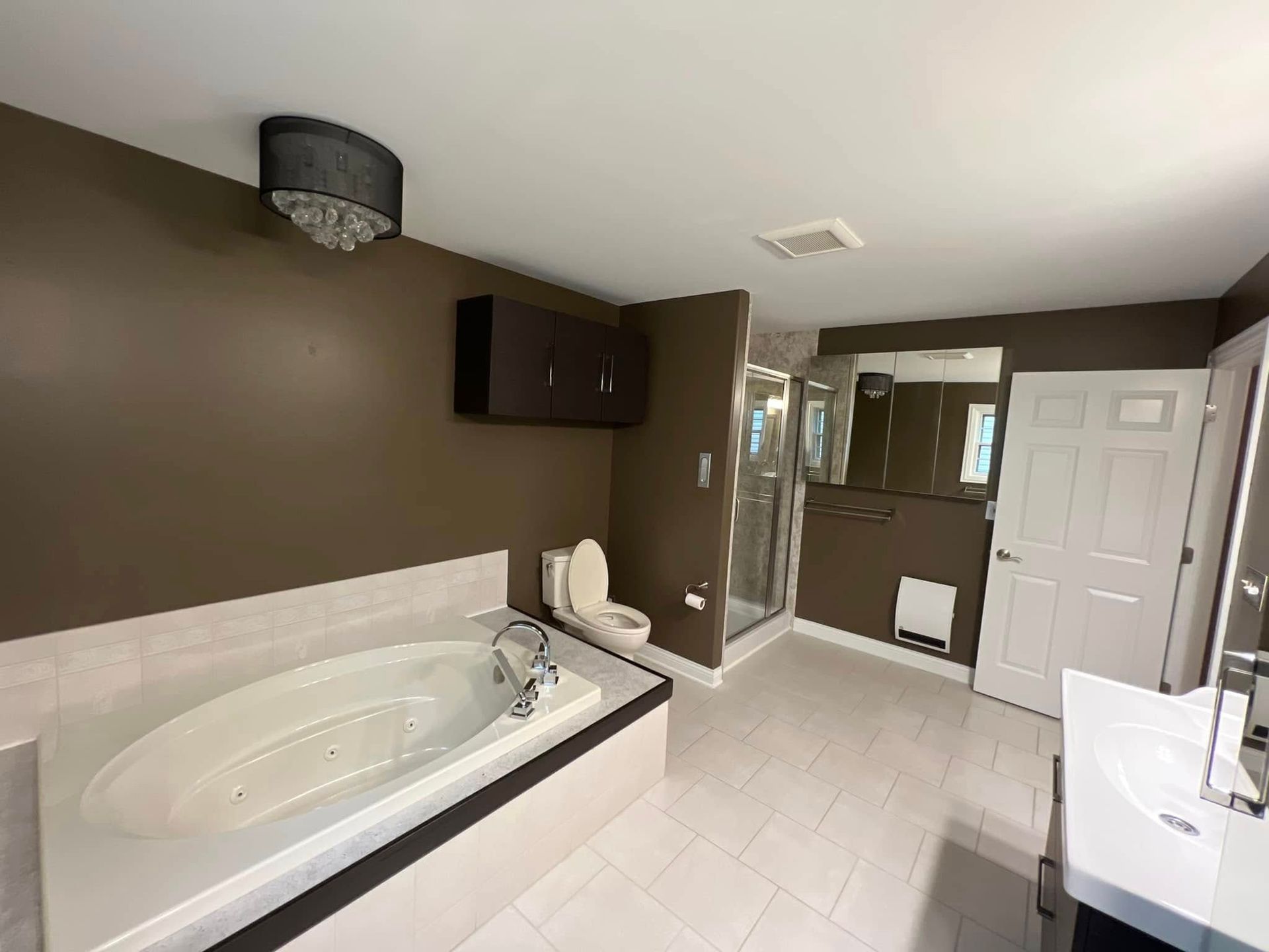 A bathroom with a tub , toilet , sink and mirror.