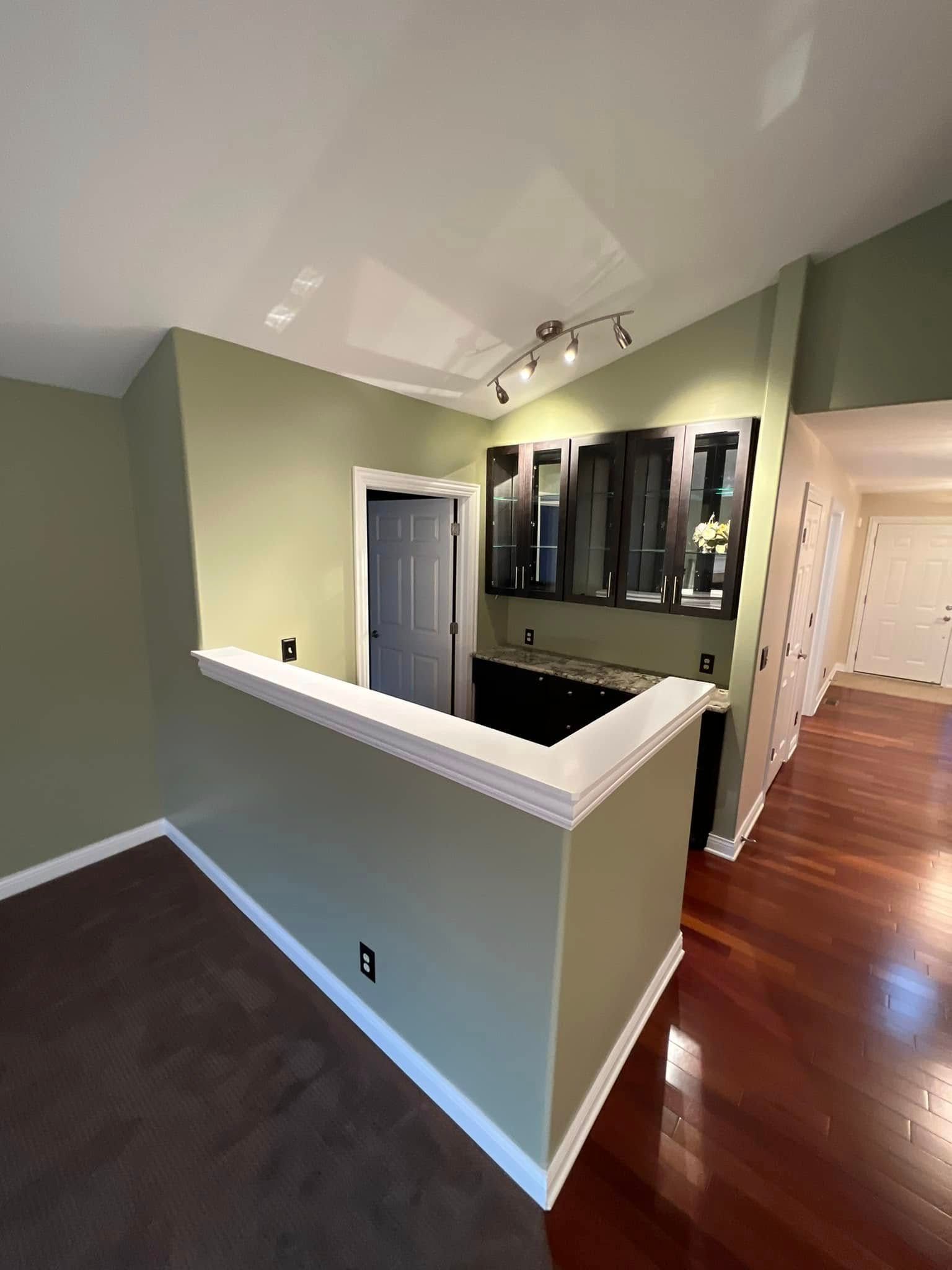 A living room with hardwood floors and green walls.
