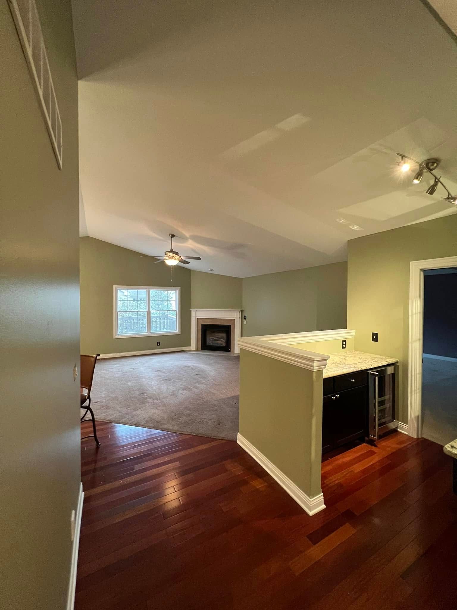 A living room with hardwood floors , a fireplace and a ceiling fan.