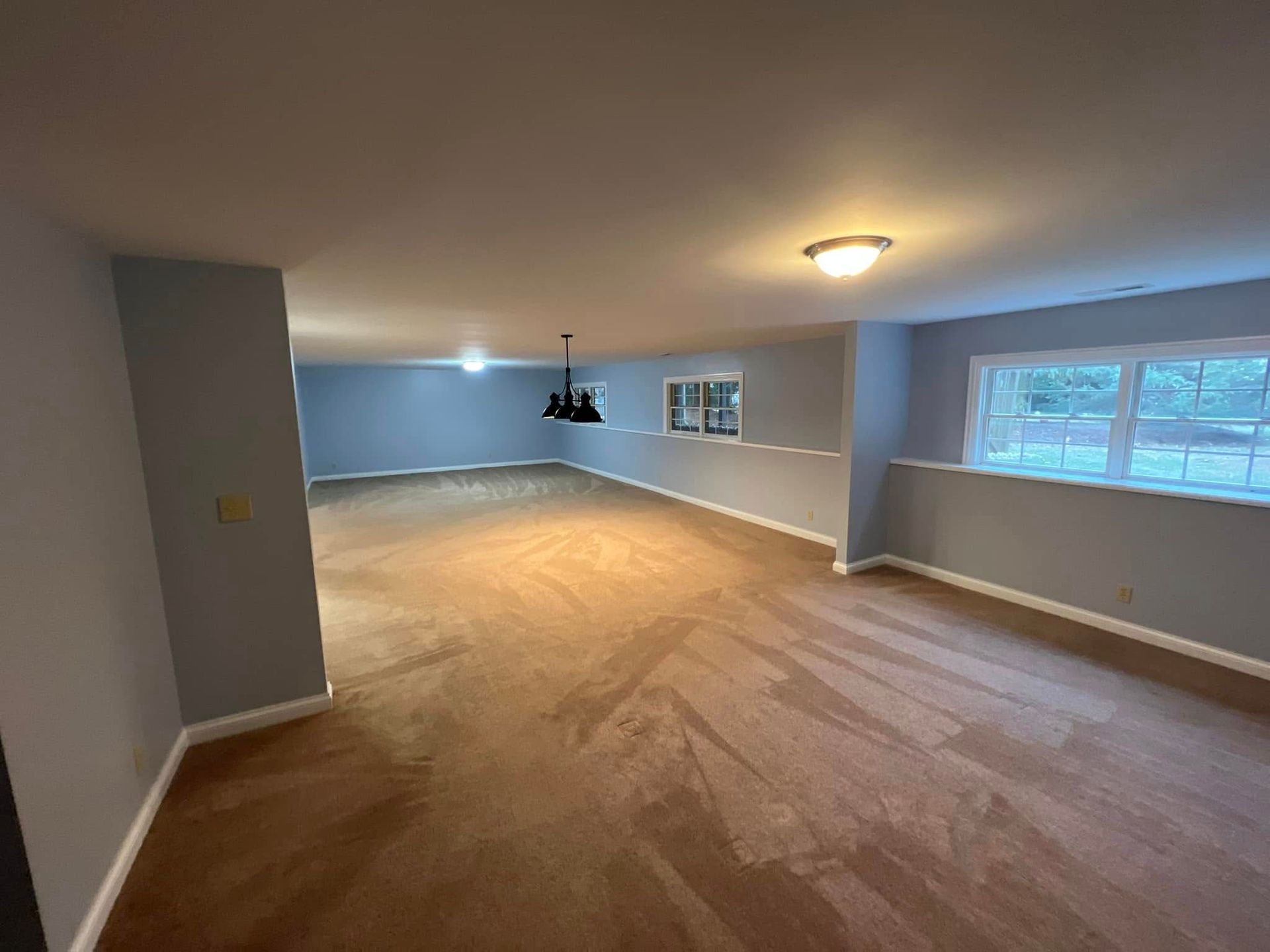 A large empty room with hardwood floors and a ceiling light.