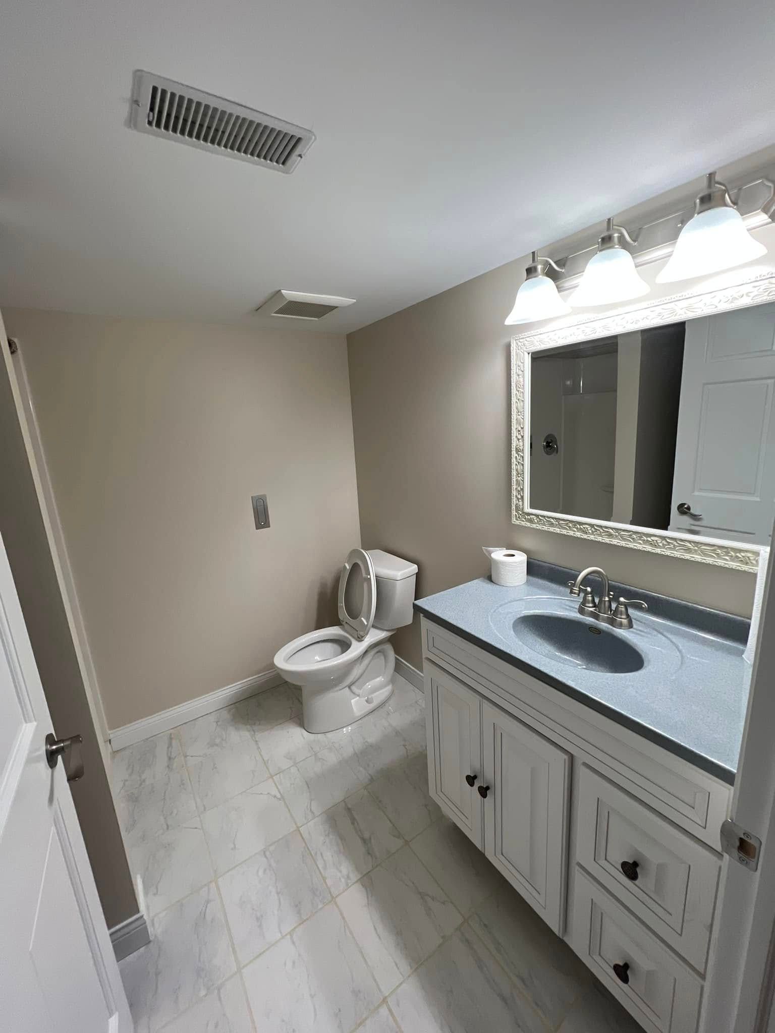 A bathroom with a toilet , sink and mirror.