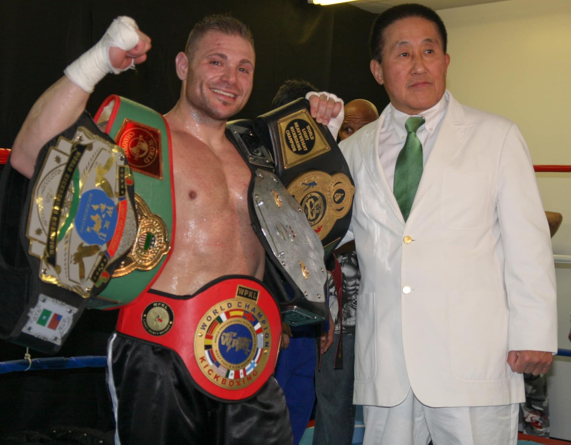 a man in a white suit stands next to a man in a green tie