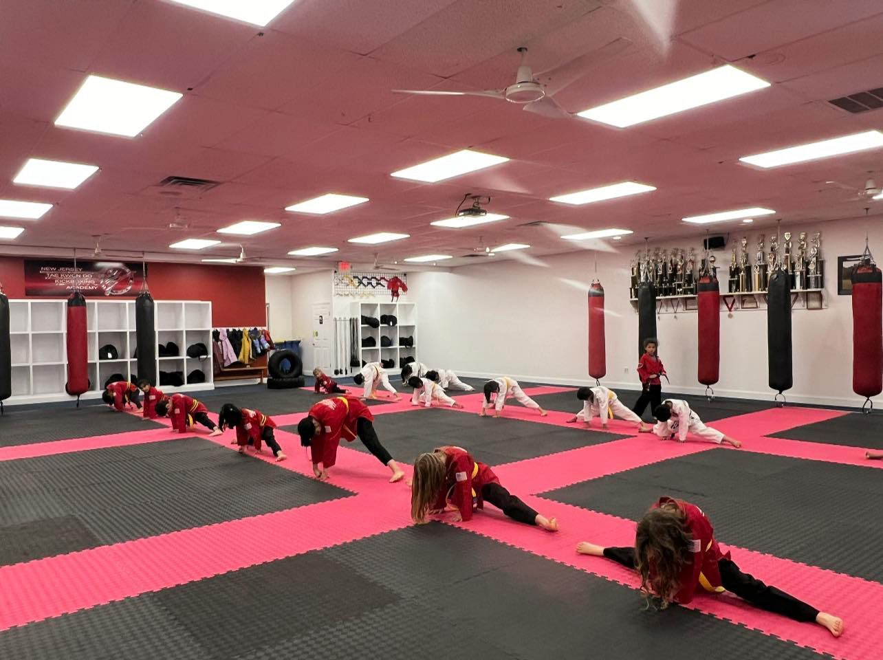 a group of children are doing stretching exercises in a gym .