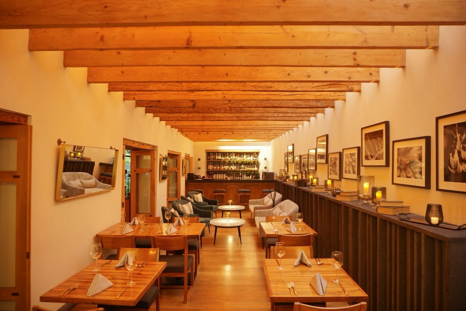 Acogedor comedor de restaurante con mesas de madera, iluminación cálida y cuadros enmarcados en las paredes.