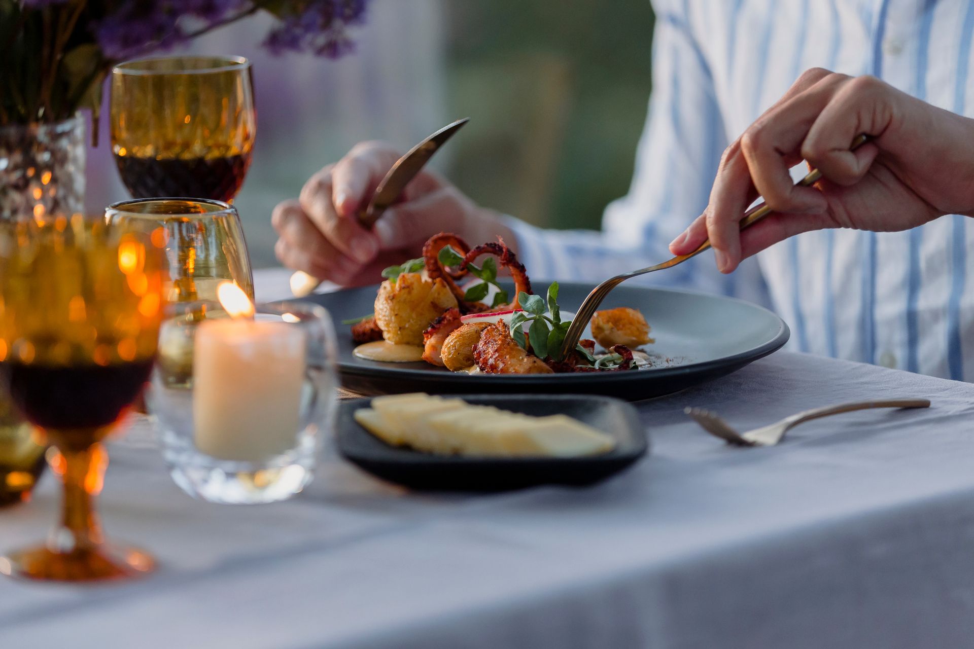 Elegante mesa de cena con copas de vino y aperitivos emplatados servidos a mano.