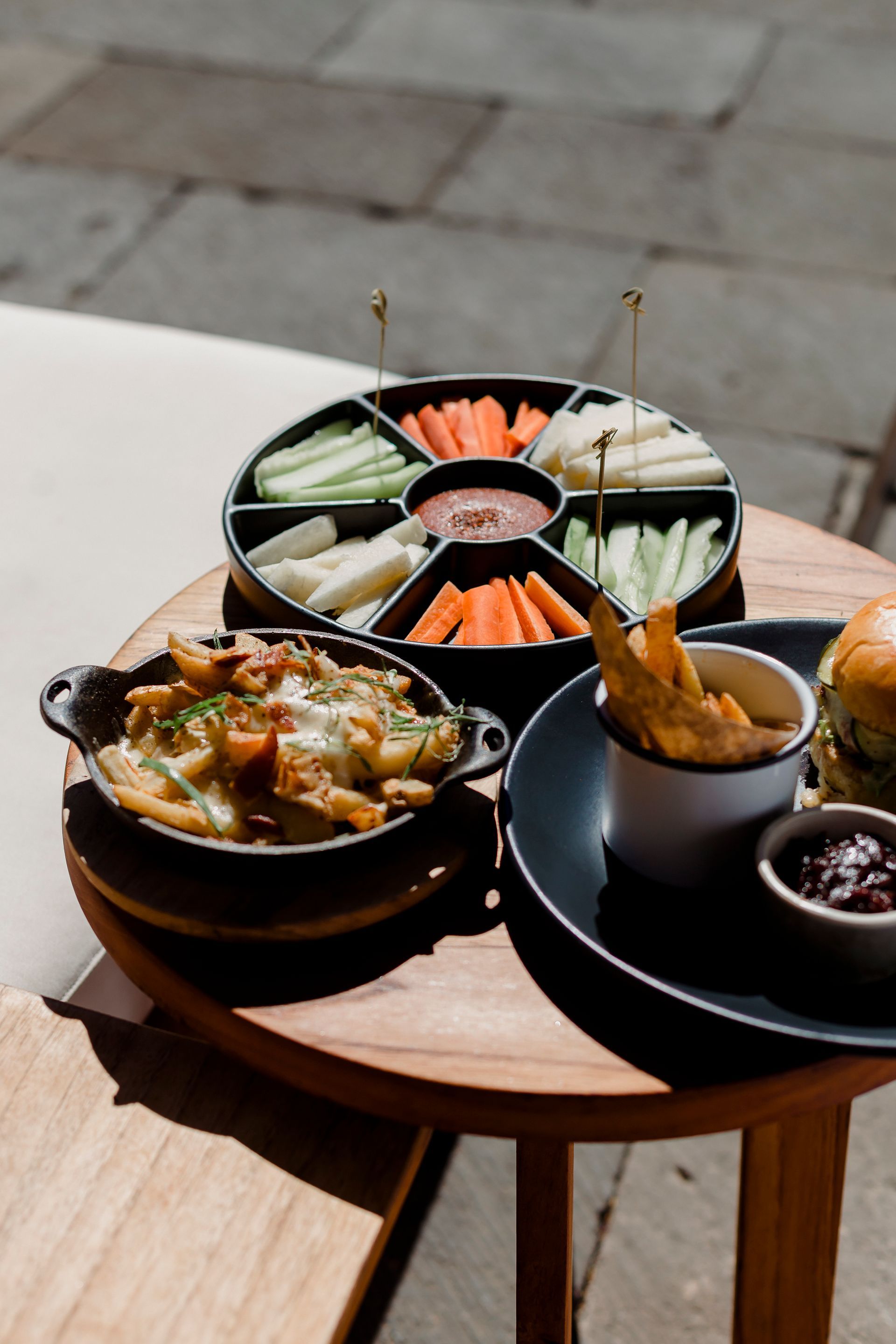 Mesa al aire libre con una bandeja de aperitivos al estilo japonés, sopa caliente y pequeños cuencos de salsas para mojar.