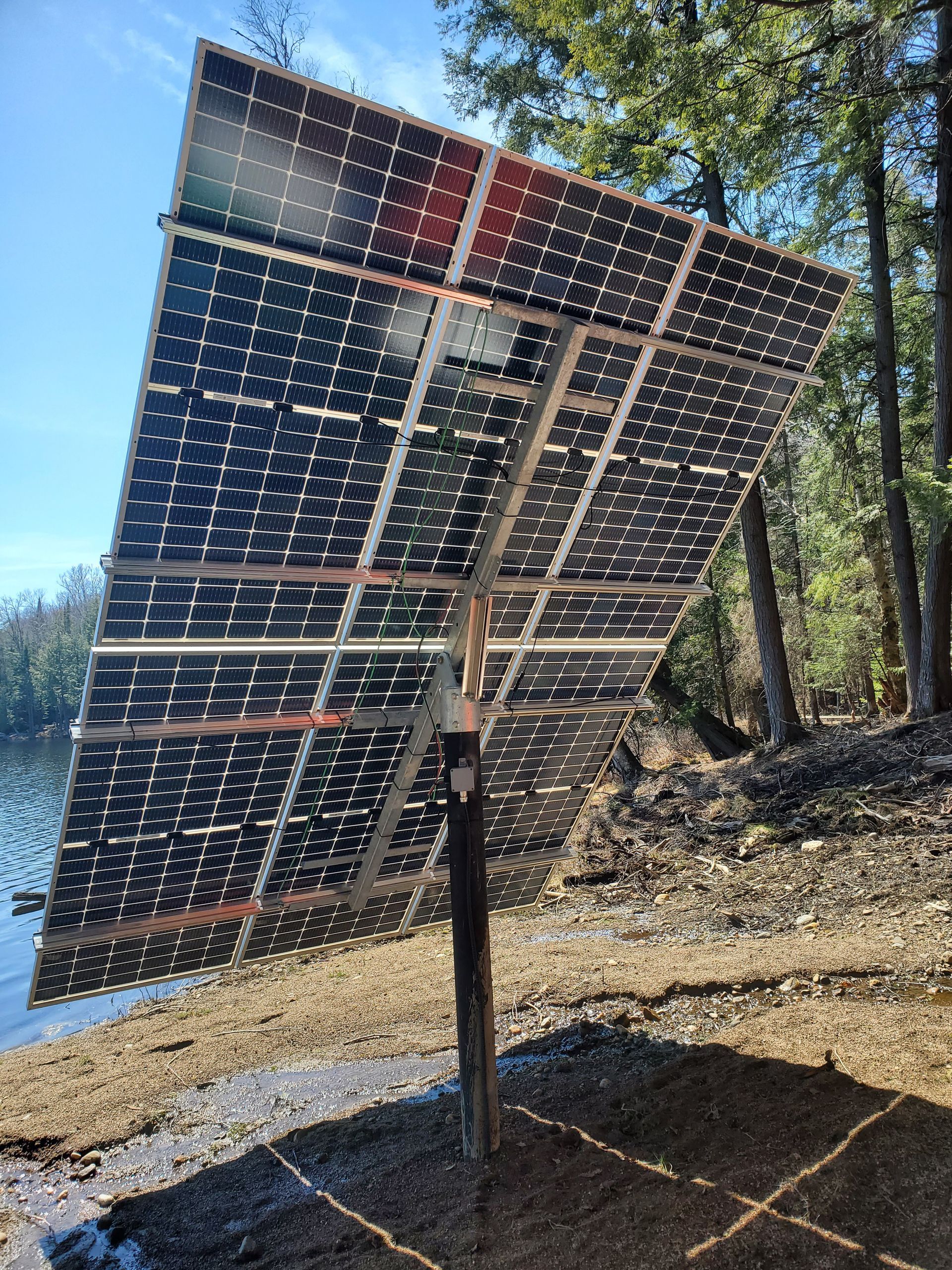 A large solar panel is sitting on the ground near a lake.