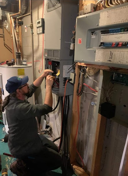 A man is working on an electrical box in a basement.