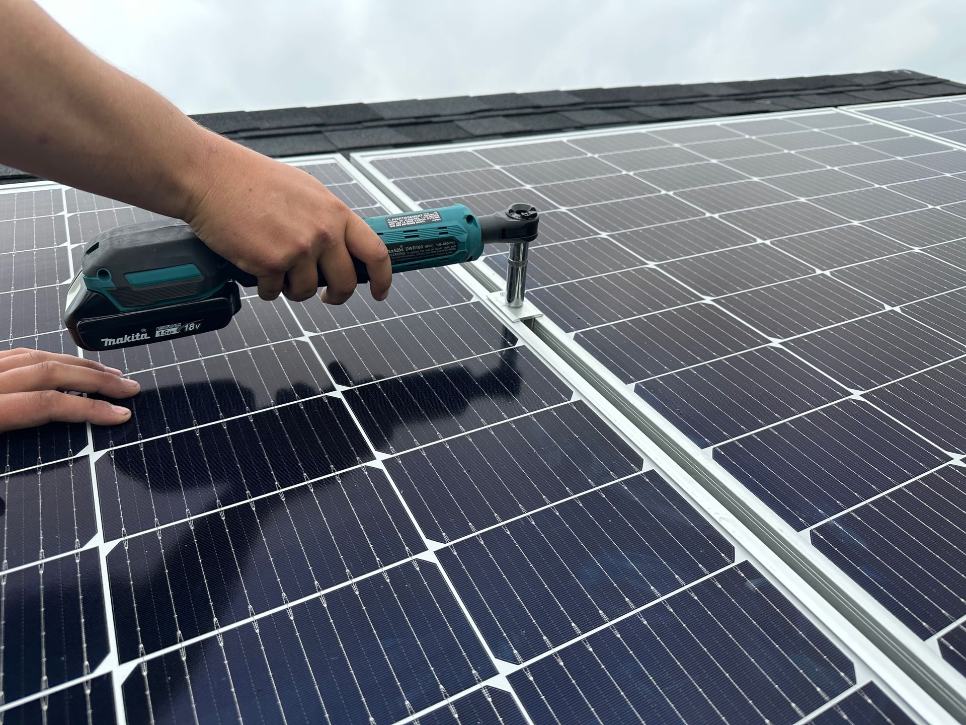 A person is working on a solar panel with a drill.