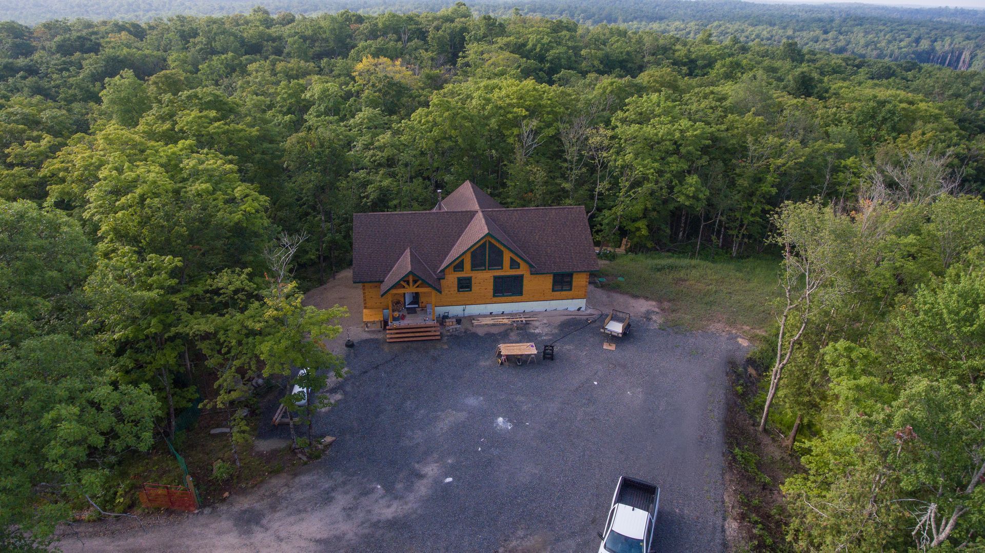 An aerial view of a log cabin in the middle of a forest.