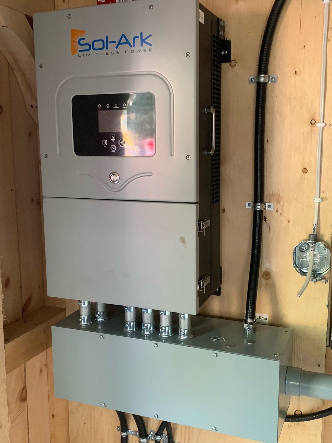 A solar panel inverter is mounted on a wooden wall.