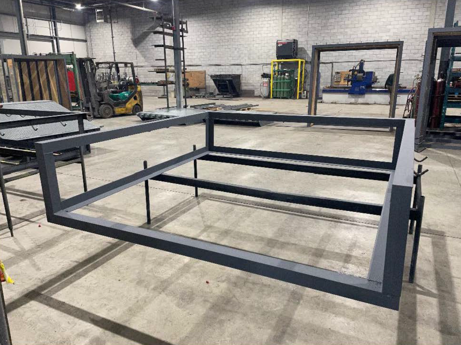 Cadre métallique gris dans une usine, probablement pour un lit ou une structure.