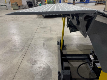 A metal ramp is sitting on a concrete floor in a warehouse.