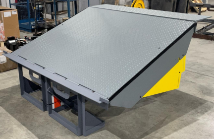 A gray and yellow ramp is sitting on the floor in a warehouse.