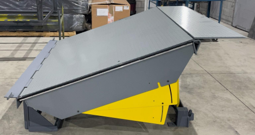 A gray and yellow machine is sitting on a concrete floor.