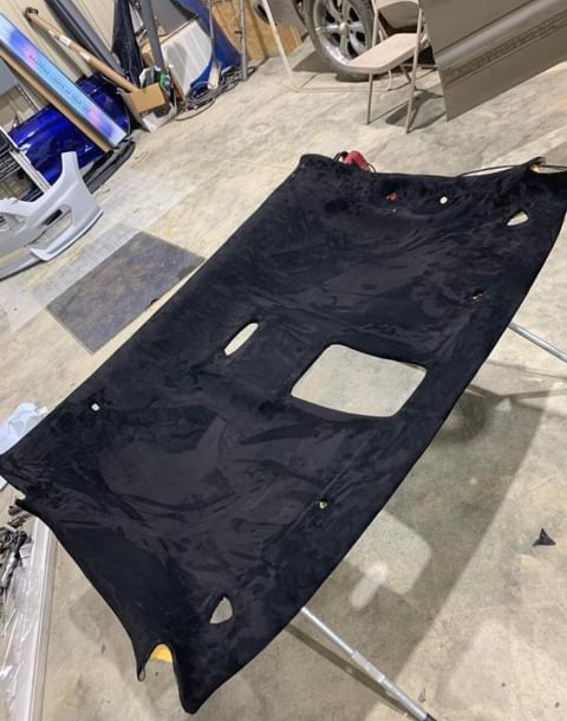 Black car headliner with holes, lying flat.