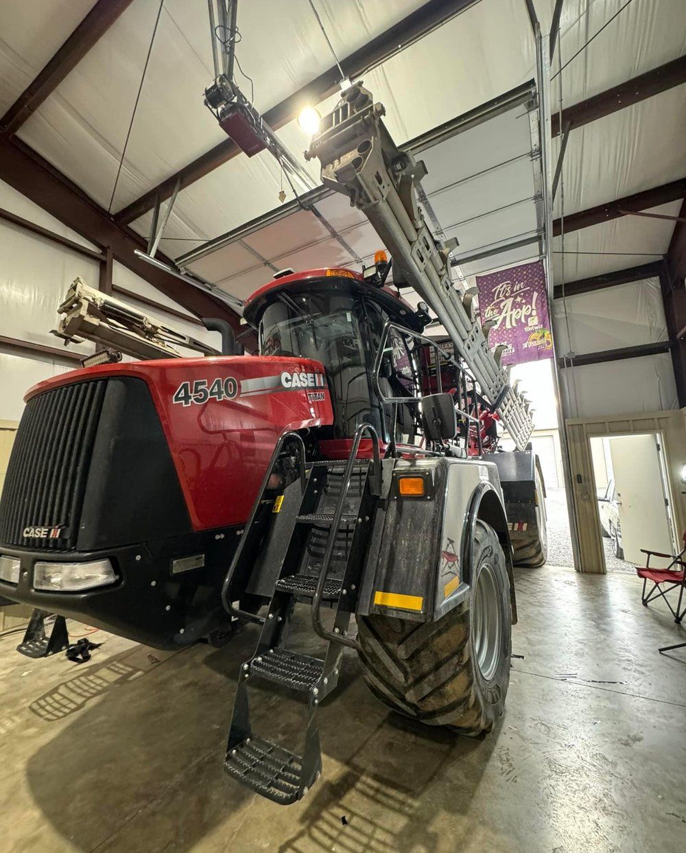 Red Case IH tractor in a workshop, tall, with extending arm overhead.