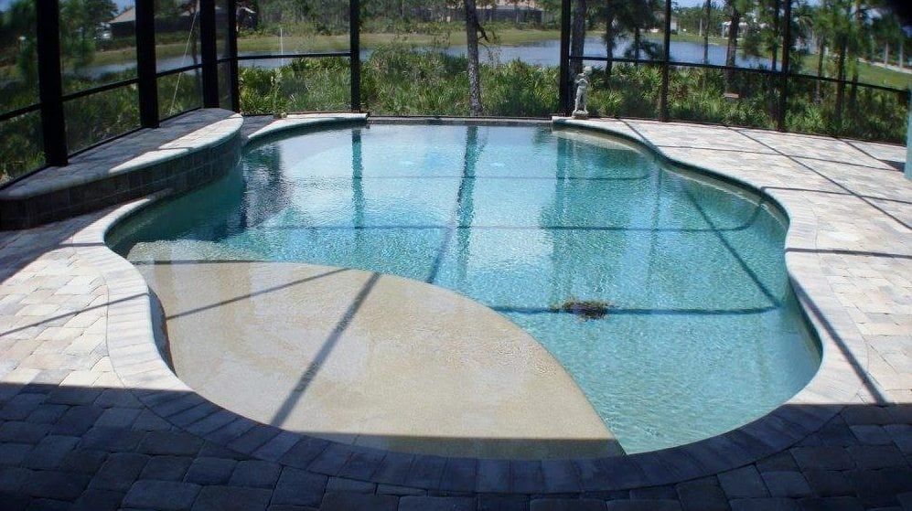Swimming pool with tanning ledge surrounded by brick patio and screened enclosure.