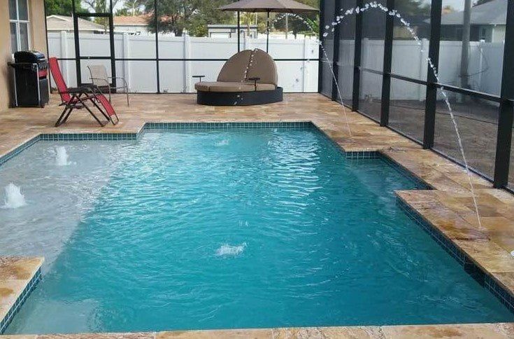 Swimming pool with fountains, chaise lounge, and patio seating enclosed by screen.