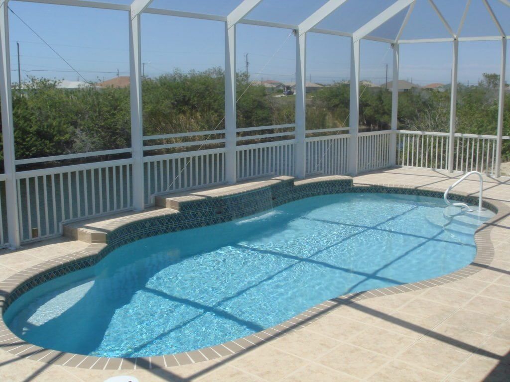 Swimming pool with blue water, white screened enclosure, and tan tile surround.