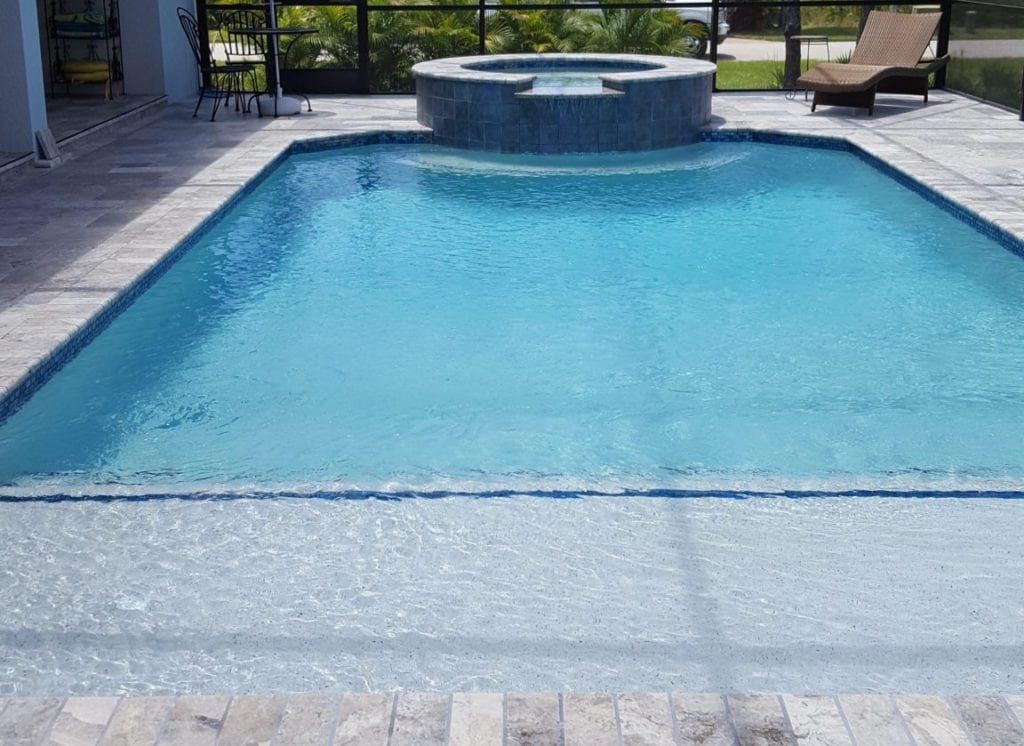 Blue pool with a raised hot tub, in a patio setting.