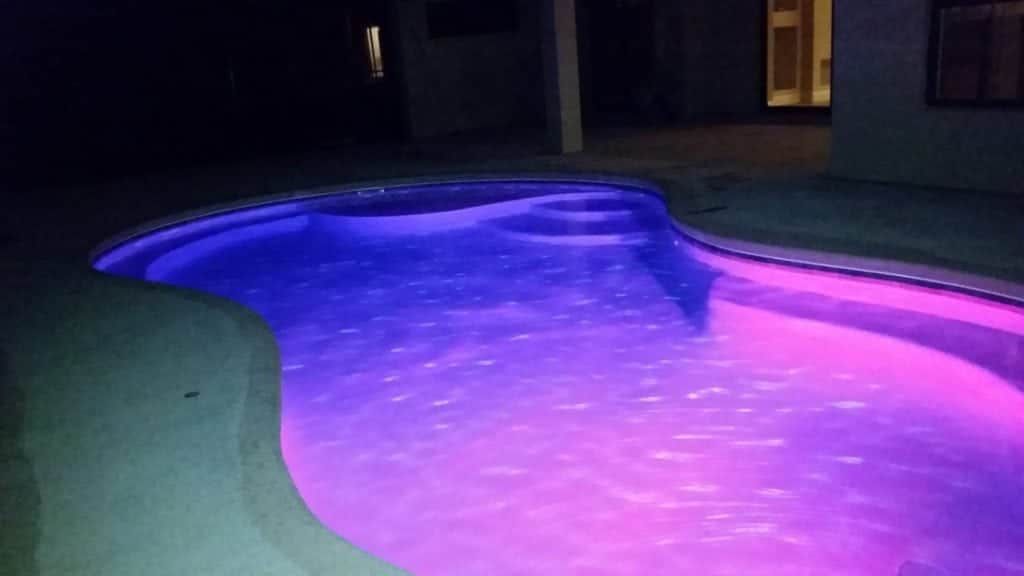 Pool with blue and purple lights at night.