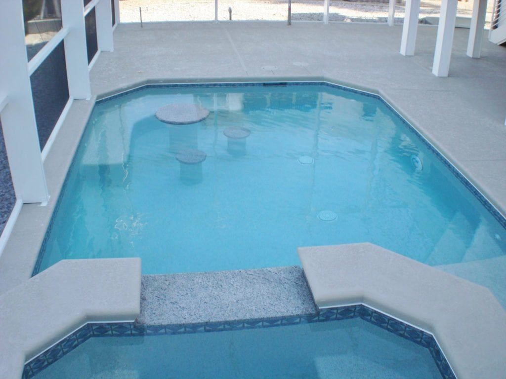 A small, blue rectangular pool with steps, seating, and a surrounding patio.