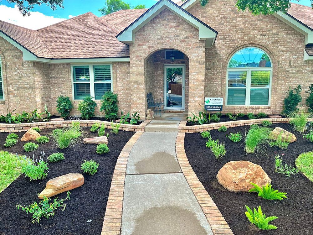 Brick house with a landscaped front yard, path leading to the front door, and plants and rocks.