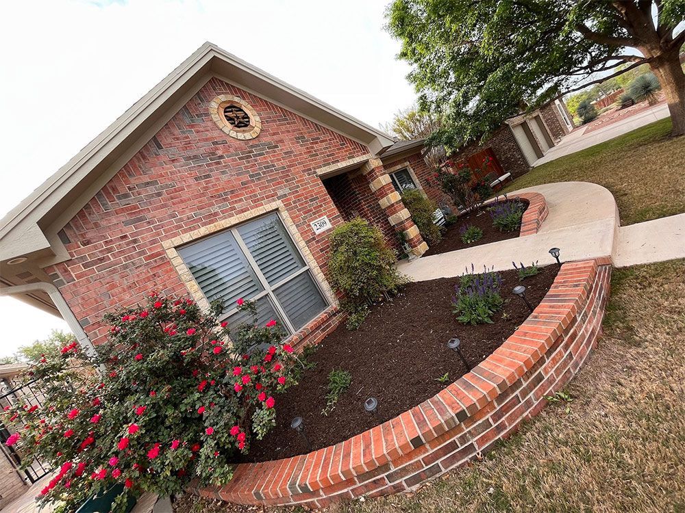 Brick house with red roses and a curved brick planter, walkway.