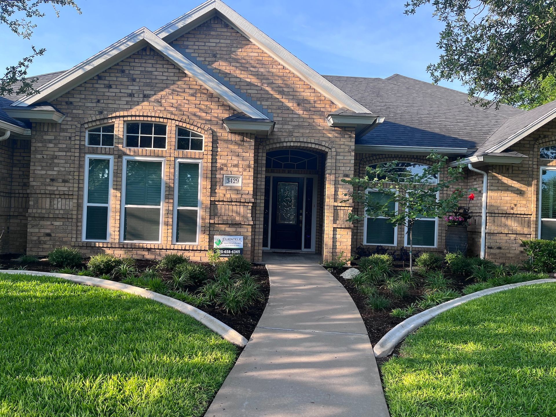 Brick house with manicured lawn and walkway leading to front door.