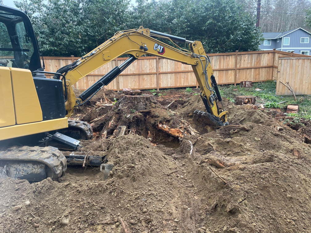 A yellow excavator is digging a hole in the ground.