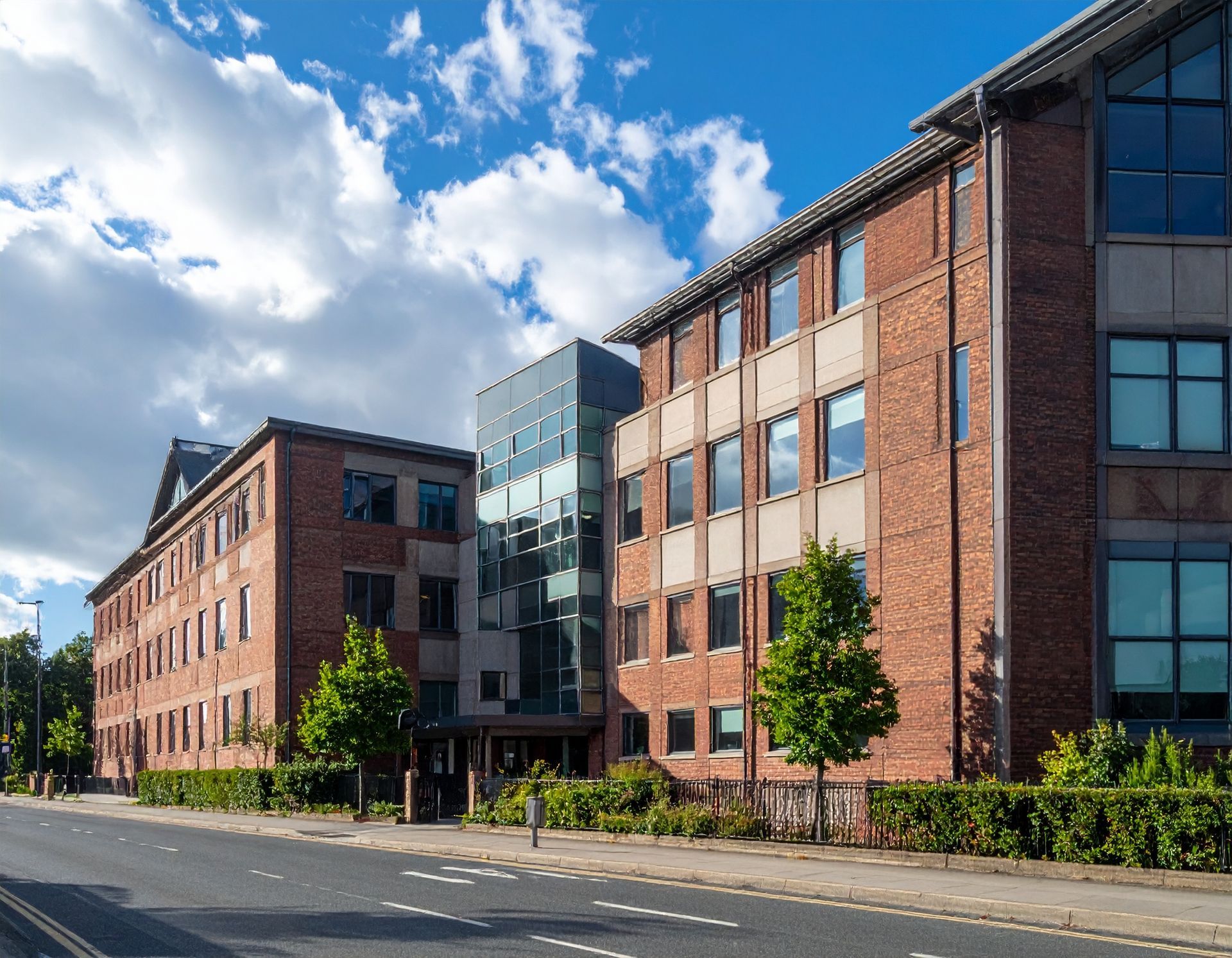 A large brick building with a lot of windows is next to a road
