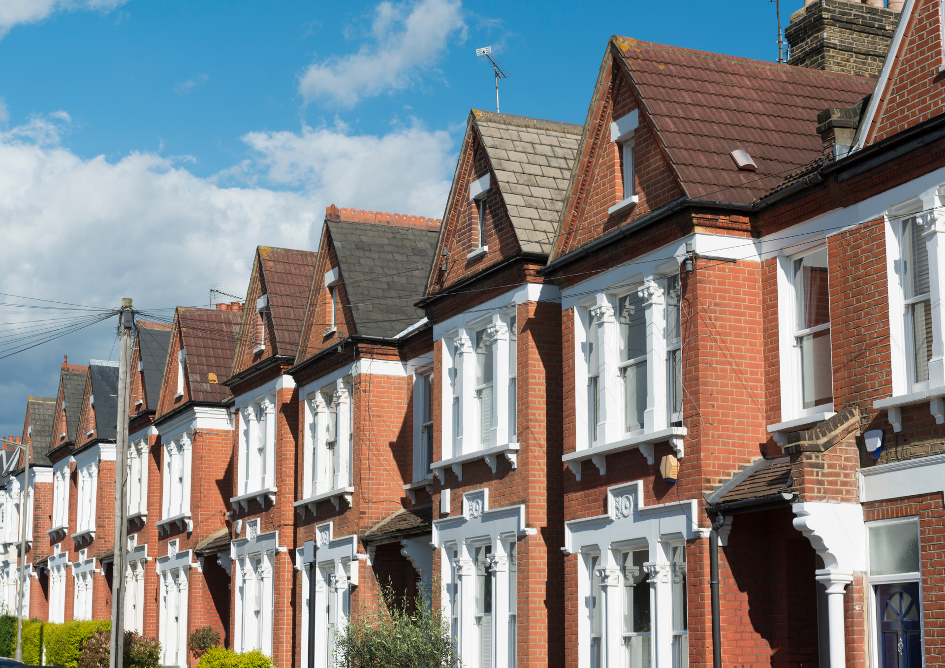 A row of red brick houses with white trim on a sunny day.
