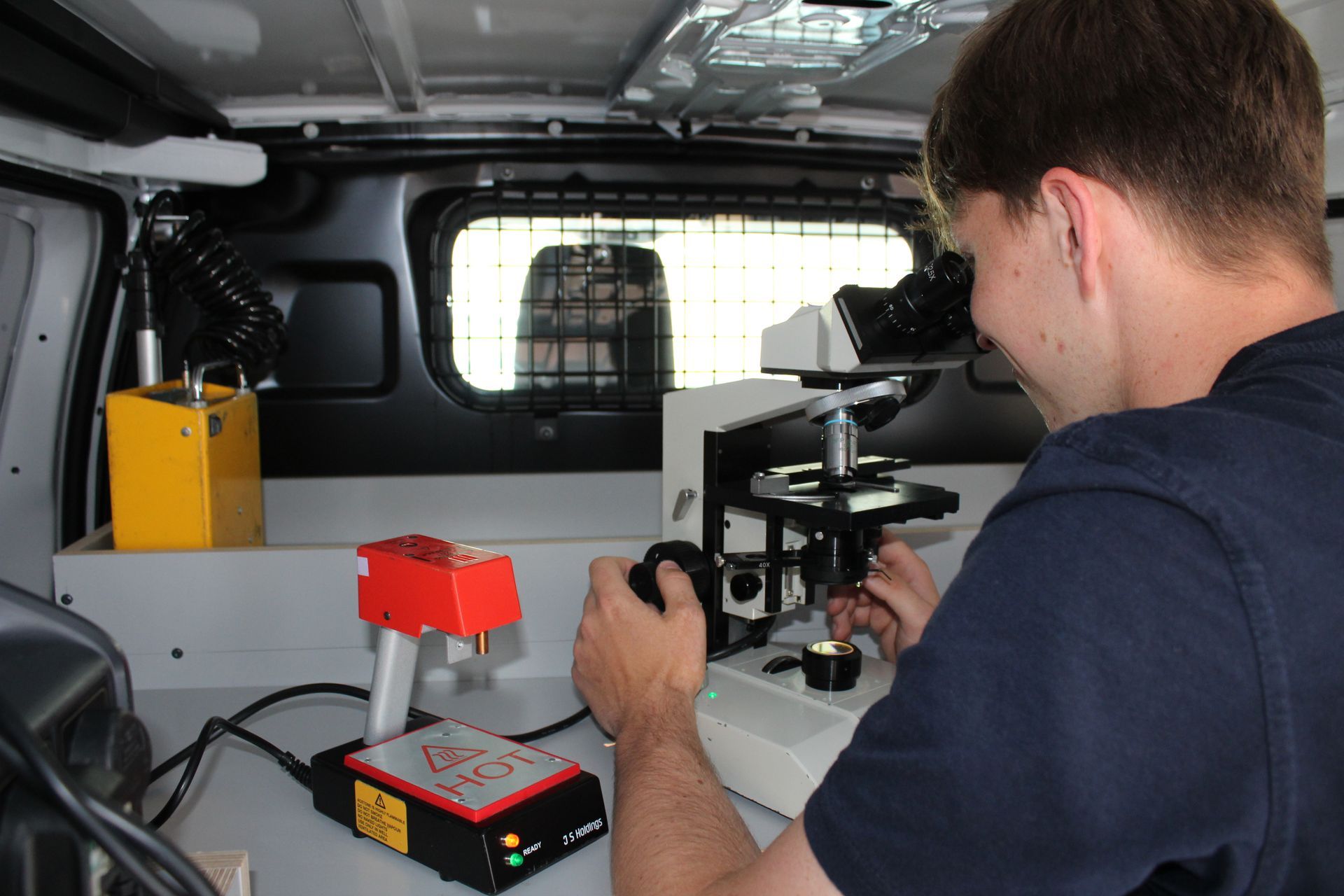A man is looking through a microscope in a van.