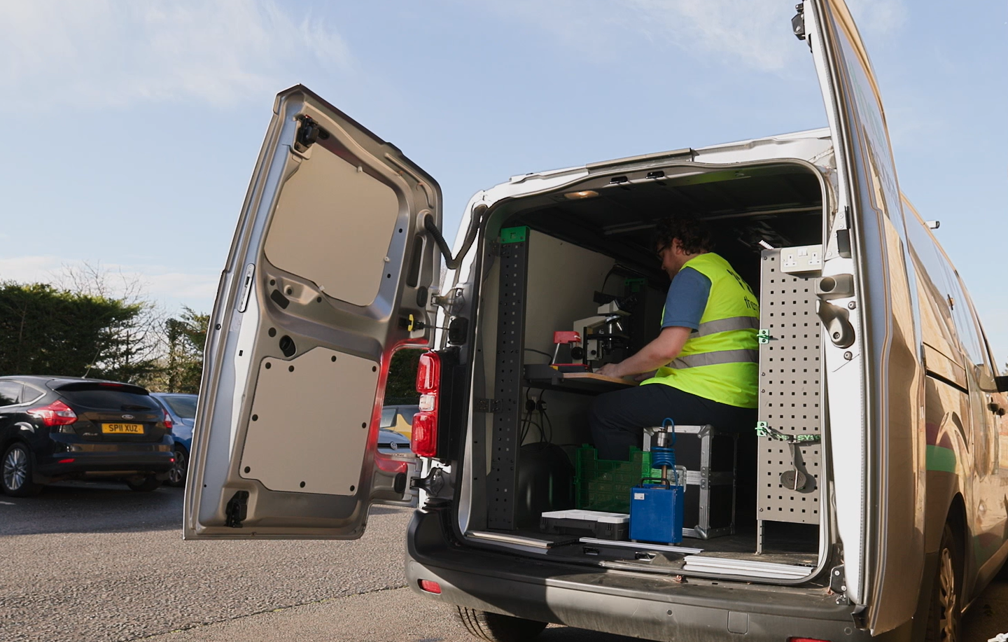 A man is looking through a microscope in a van.