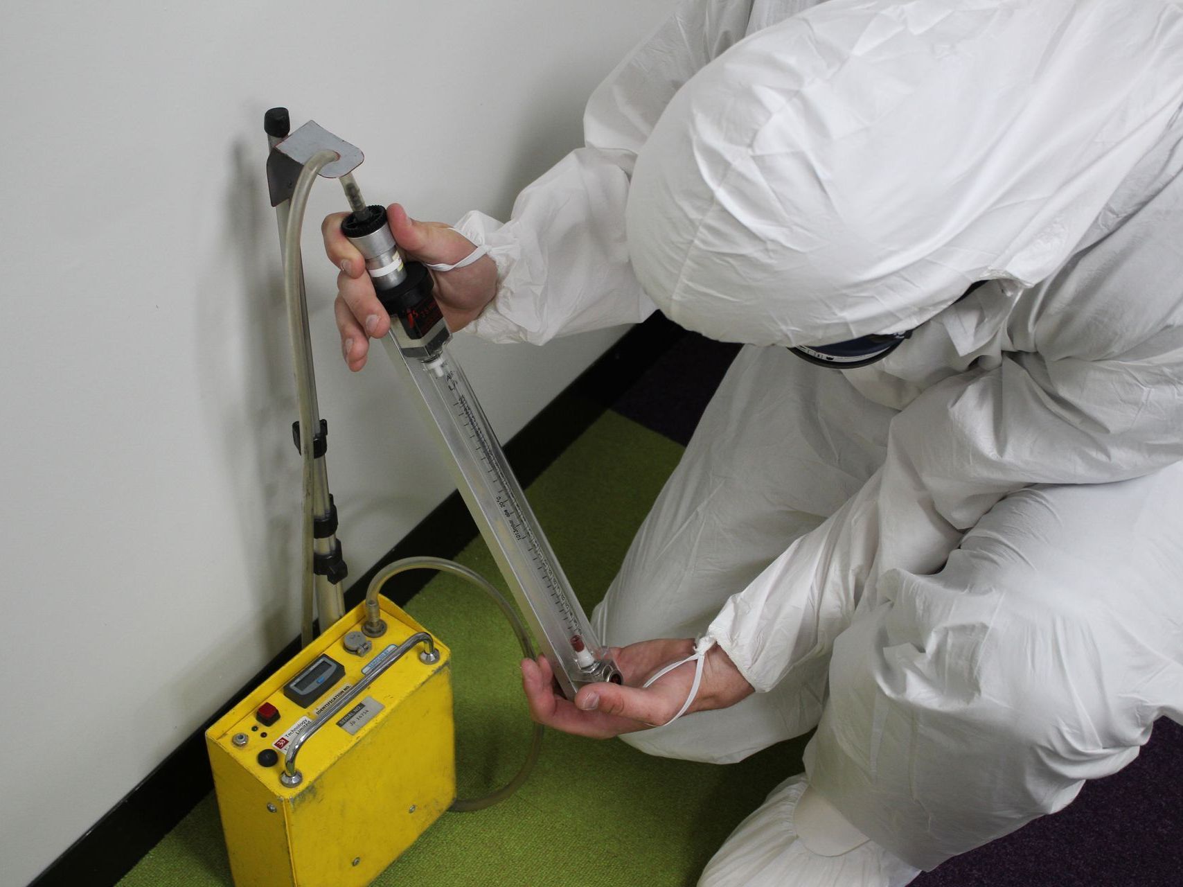 A person in a white suit is working on a yellow device